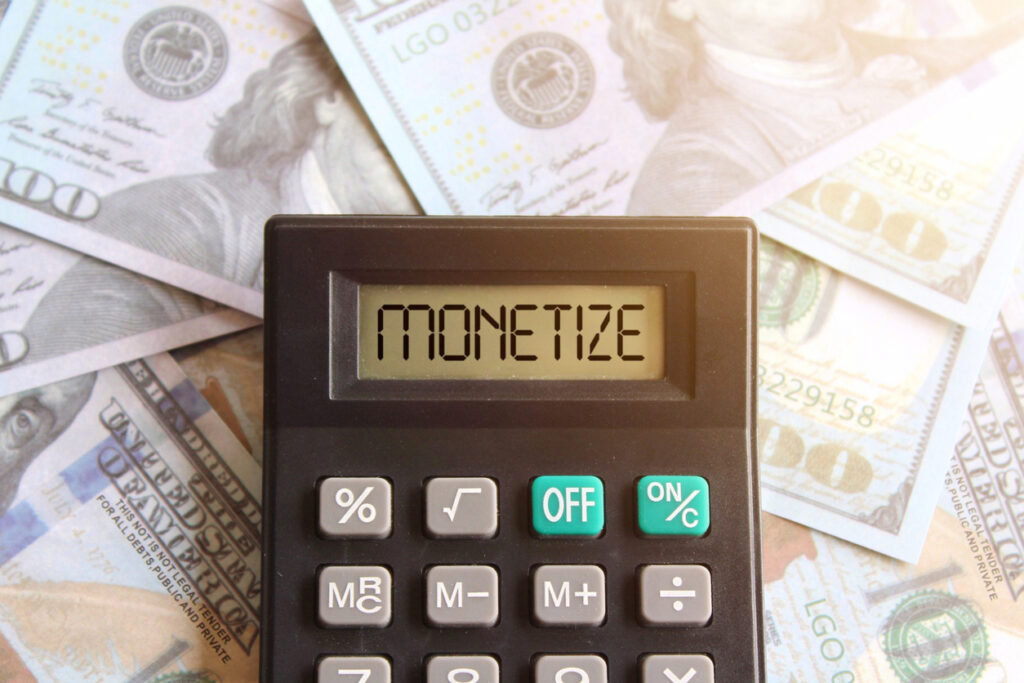 Top-view-image-of-calculator-with-text-MONETIZE-on-display-and-money-Content-monetization-concept