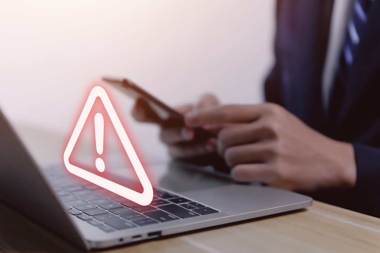 Businessman-using-laptop-showing-warning-triangle-and-exclamation-mark-A-warning-about-a-dangerous-problem-is-showing-up-on-your-computer