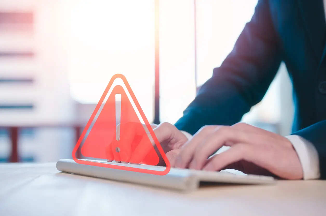 Risk-and-cyber-security-on-internet-network-Businessman-using-computer-keyboard-with-triangle-caution-warning-exclamation-sign-for-notification-error-and-maintenance-concept
